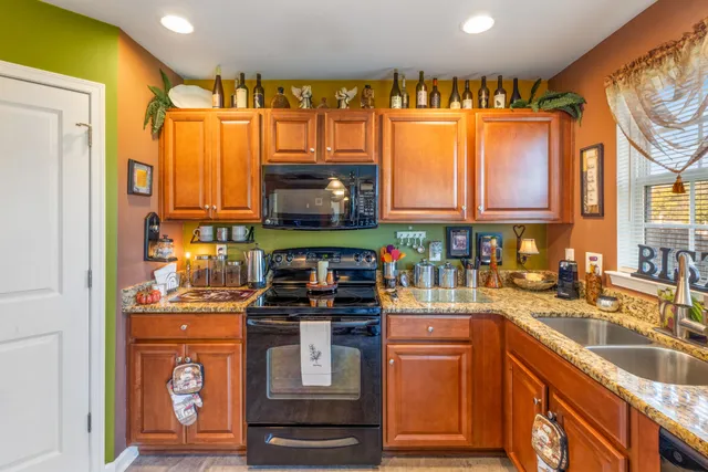 a kitchen with granite countertop a stove a sink and a refrigerator