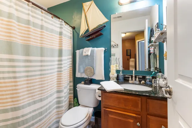 a bathroom with a granite countertop toilet sink and mirror