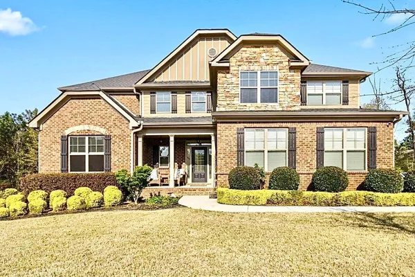 a kitchen with granite countertop a refrigerator a stove a kitchen island and chairs with wooden floor