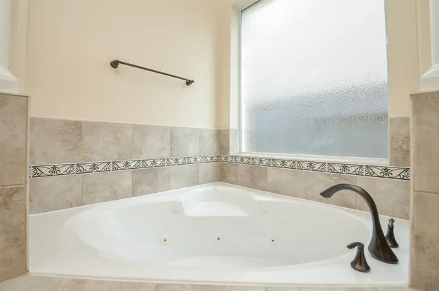 a bathroom with a granite countertop double vanity sink and a bathtub