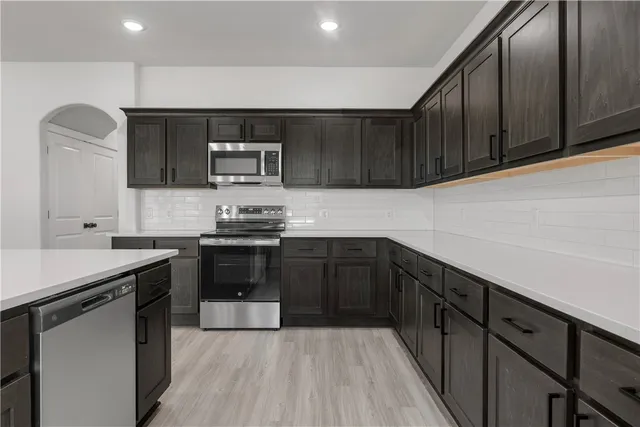 a kitchen with granite countertop a sink cabinets and stainless steel appliances