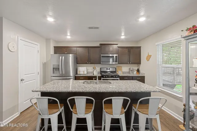 a kitchen with granite countertop kitchen island stainless steel appliances a sink and cabinets