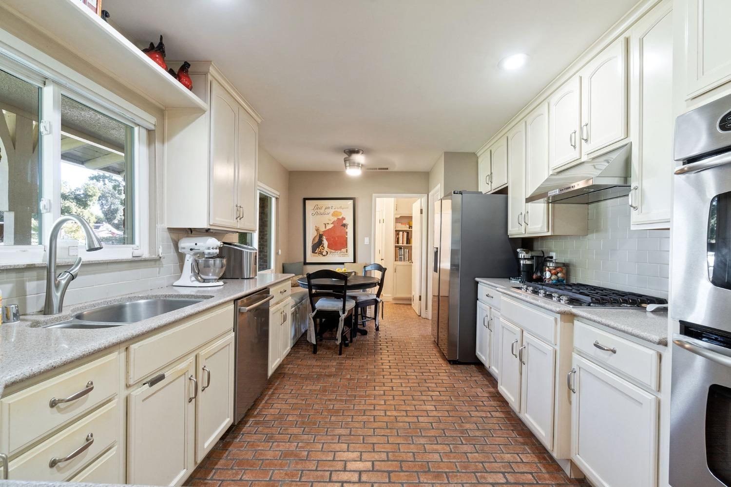 1323 West San Ramon Avenue Fresno, CA 93711 - Photo 6 of 30 a kitchen with stainless steel appliances granite countertop a stove top oven a sink dishwasher a refrigerator and white cabinets with wooden floor