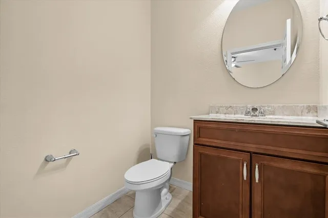 a bathroom with a granite countertop toilet sink mirror and vanity