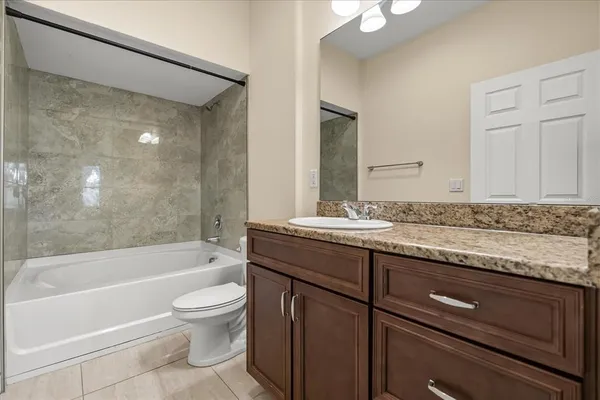 a bathroom with a granite countertop sink a toilet and bathtub