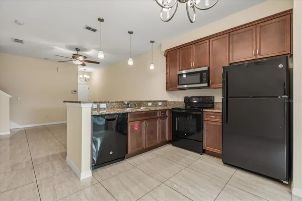 a kitchen with granite countertop a refrigerator and a stove top oven