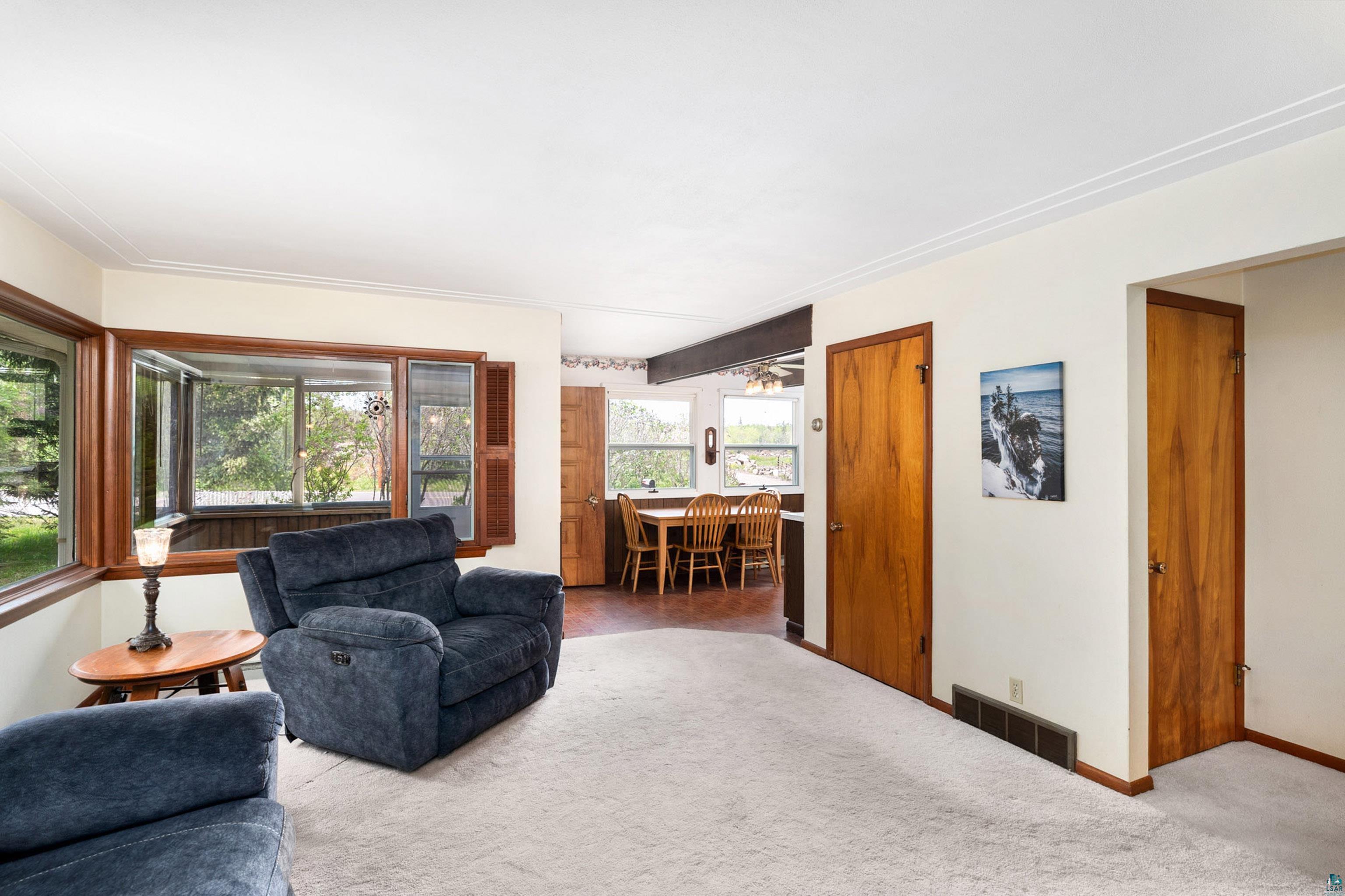 4808 Midway Road Duluth, MN 55811 - Photo 17 of 57 Living area featuring light-toned carpeting, white walls, and a bay window with a wood frame and shutters