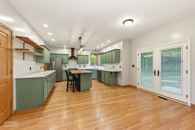 a large kitchen with stainless steel appliances kitchen island a large counter top and view of living room
