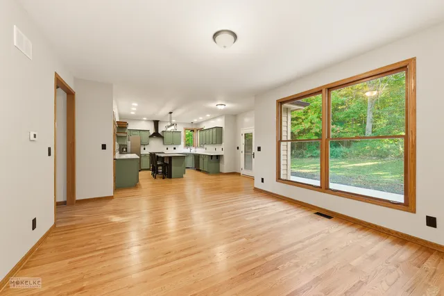 a view of an empty room with kitchen view and a window