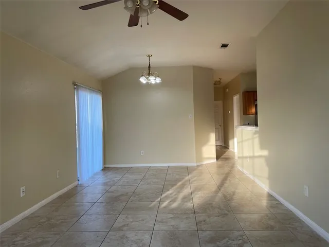a view of an empty room with a chandelier fan