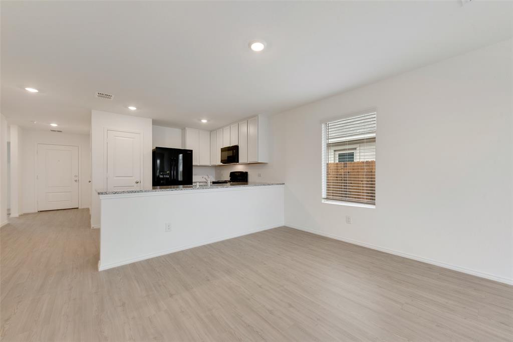 1624 Crested Way Fort Worth, TX 76140 - Photo 1 of 14 Kitchen featuring white cabinetry, light stone counters, light hardwood / wood-style flooring, kitchen peninsula, and black appliances