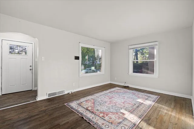 a view of an empty room with window and wooden floor