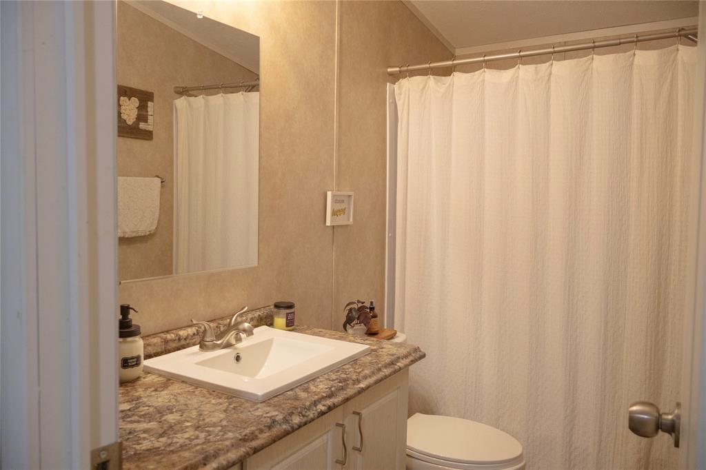 130 Firefly Drive Springtown, TX 76082 - Photo 14 of 25 a bathroom with a granite countertop sink and a mirror