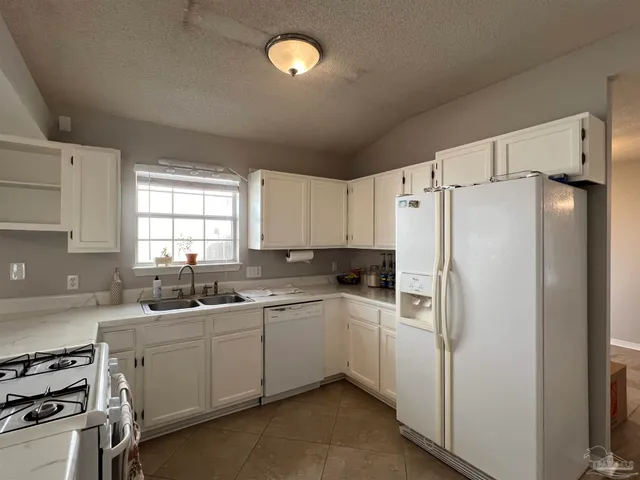 a kitchen with a sink a refrigerator a window and cabinets
