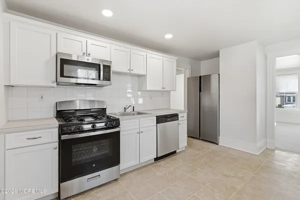 a kitchen with stainless steel appliances white cabinets and a stove top oven