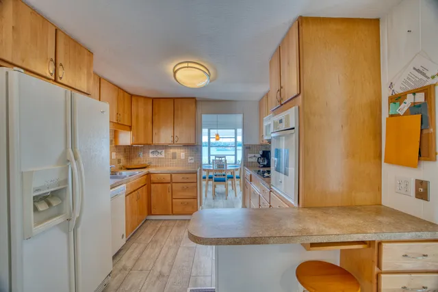 a kitchen with stainless steel appliances granite countertop a stove a sink dishwasher and white cabinets with wooden floor