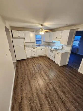 a living room with kitchen island granite countertop wooden floor and a sink