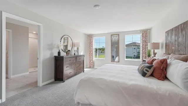 a spacious bedroom with a bed and a dresser next to a window