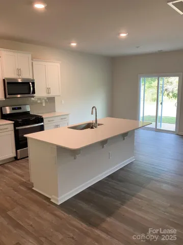 a kitchen with stainless steel appliances granite countertop a sink a stove and a wooden floors