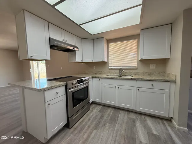 a kitchen with stainless steel appliances granite countertop a stove a sink and white cabinets
