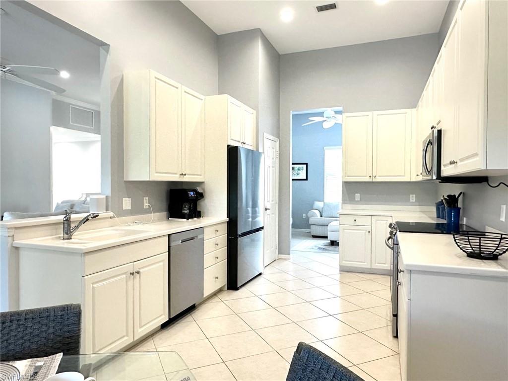 12259 Toscana Way, Unit 202 Bonita Springs, FL 34135 - Photo 14 of 40 a kitchen with a sink a stove a refrigerator and white cabinets with wooden floor