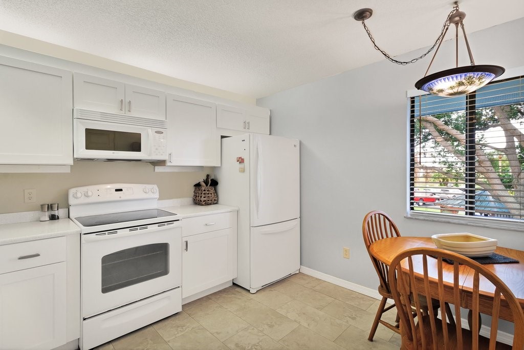 9637 Riverside Drive, Unit 3 Sebastian, FL 32958 - Photo 11 of 36 a kitchen with stainless steel appliances granite countertop a stove a refrigerator a microwave oven with a dining table and chairs