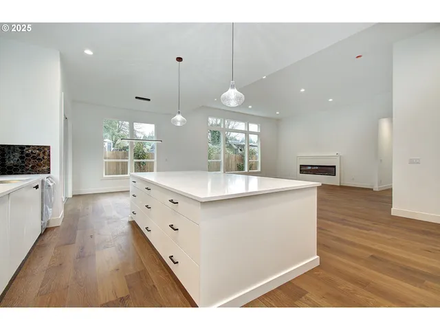 a large kitchen with kitchen island a sink dishwasher a stove a dining table and chairs with wooden floor