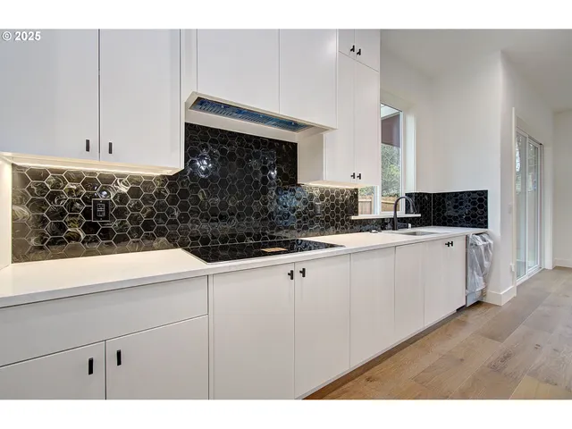 a kitchen with white cabinets a sink and dishwasher
