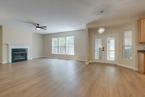 an empty room with wooden floor fireplace and windows