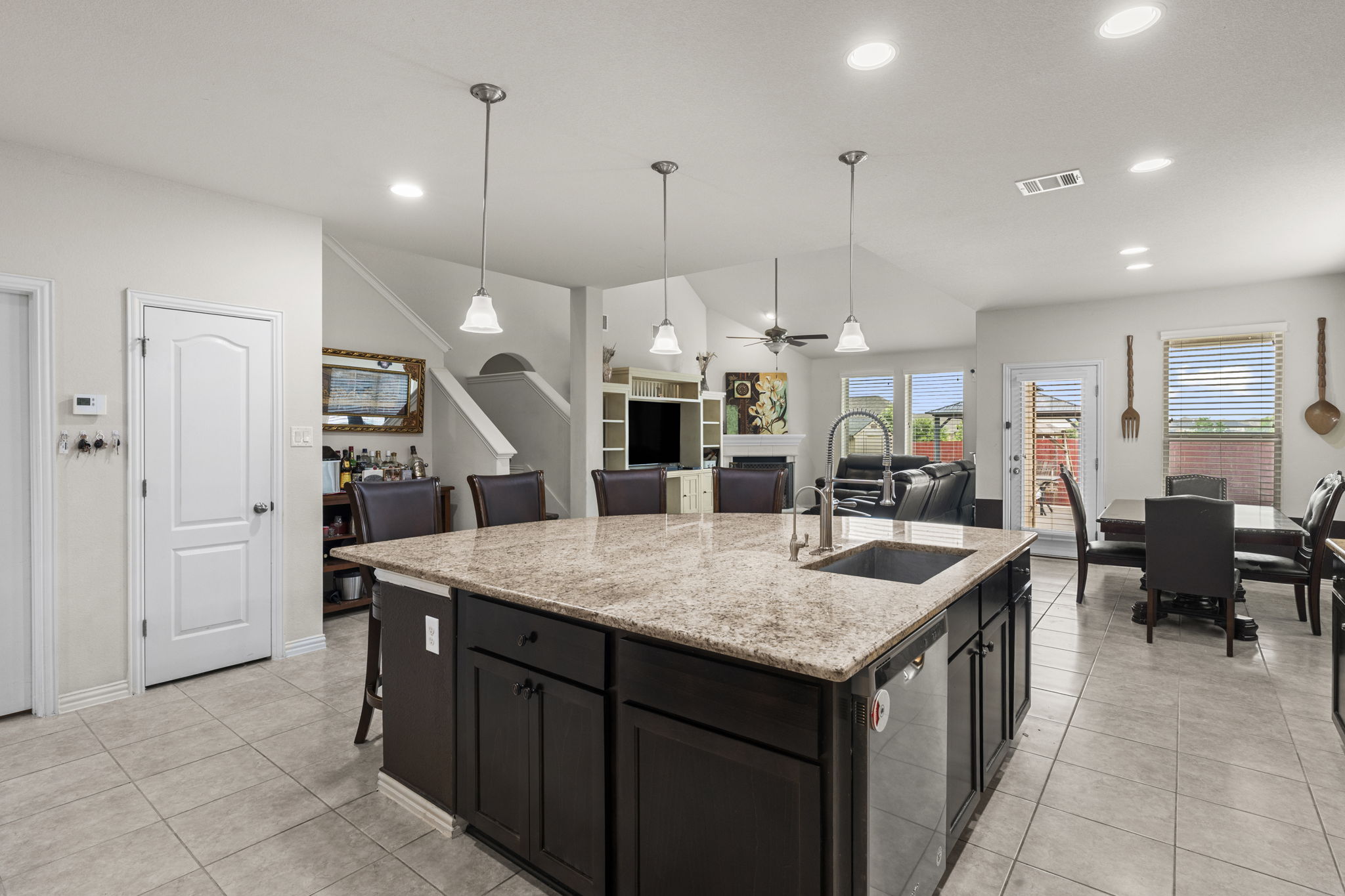 373 Rough Bark Street Buda, TX 78610 - Photo 4 of 39 A grand central island anchors this open-concept kitchen, flowing seamlessly into dining and living areas, perfect for entertaining.