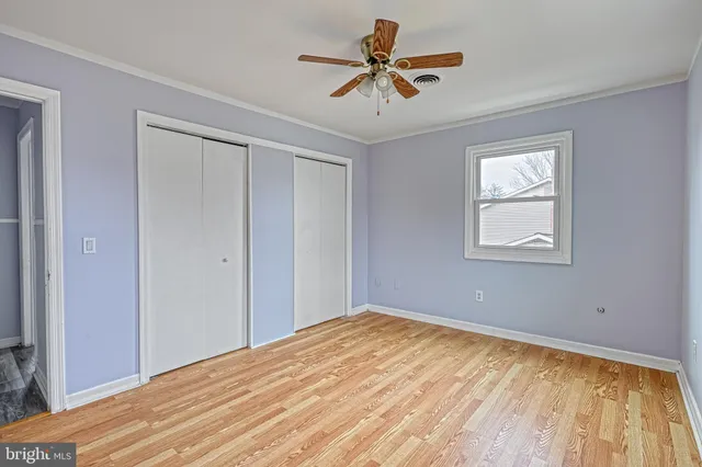 a view of an empty room with wooden floor and stairs
