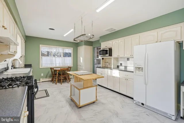 a kitchen with a refrigerator a stove a sink dishwasher with a dining table and chairs