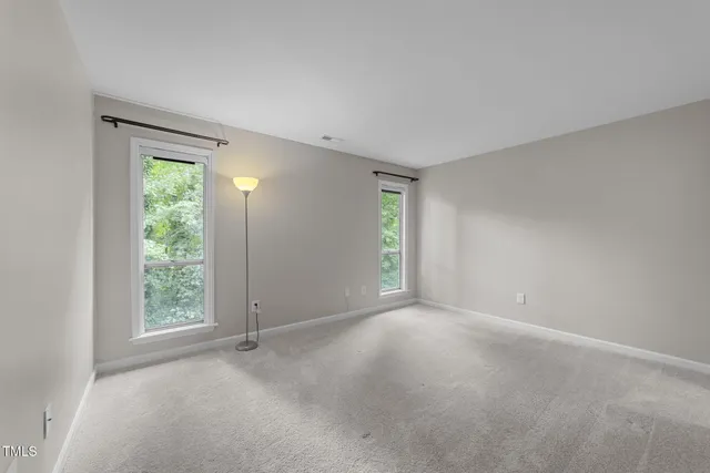 a view of an empty room with chandelier fan and fire place