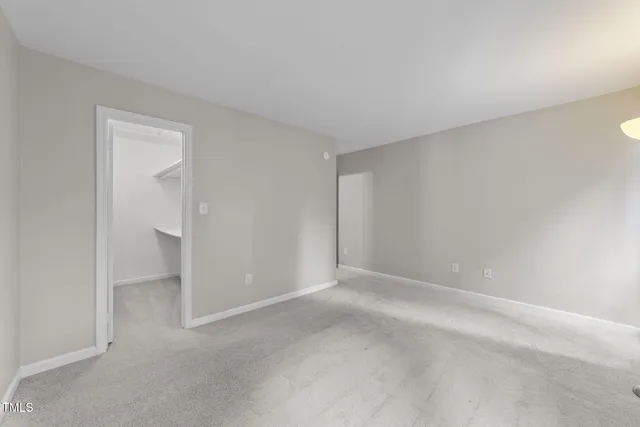 a view of an empty room with window and closet area