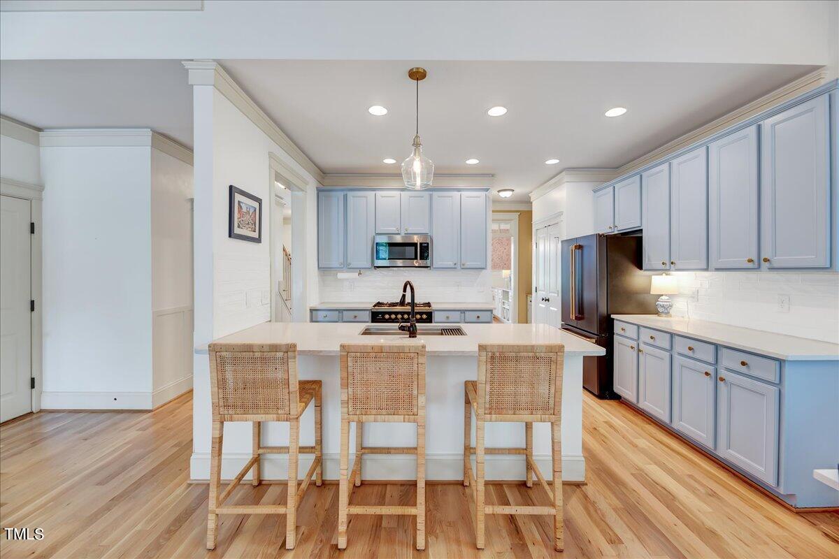 2901 Brighton Bluff Drive Apex, NC 27539 - Photo 6 of 35 a kitchen with kitchen island granite countertop wooden floors white cabinets and stainless steel appliances