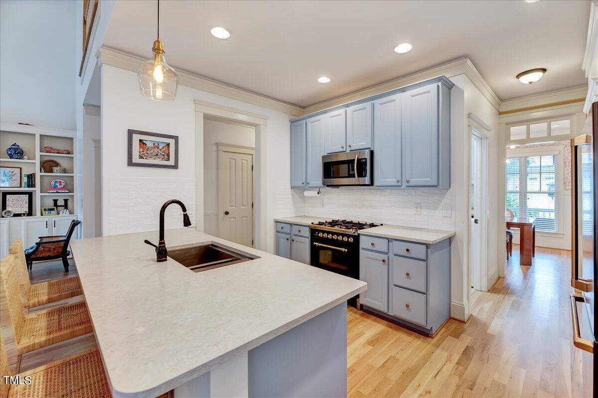 2901 Brighton Bluff Drive Apex, NC 27539 - Photo 8 of 35 a kitchen with stainless steel appliances granite countertop a stove top oven a sink a dining table and chairs with wooden floor