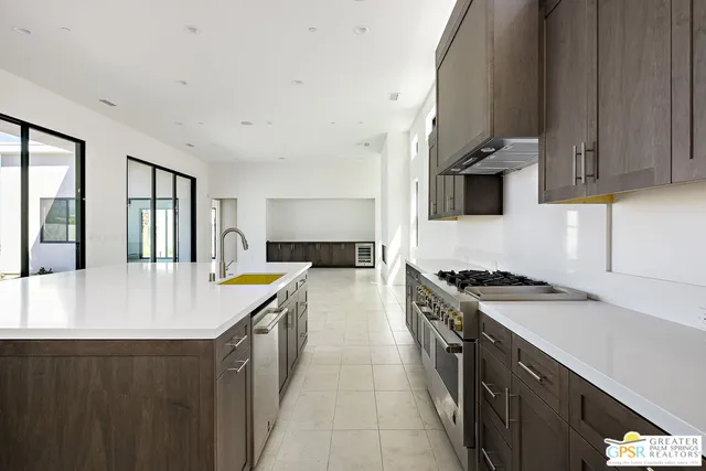 a large kitchen with stainless steel appliances granite countertop a sink a stove and a refrigerator