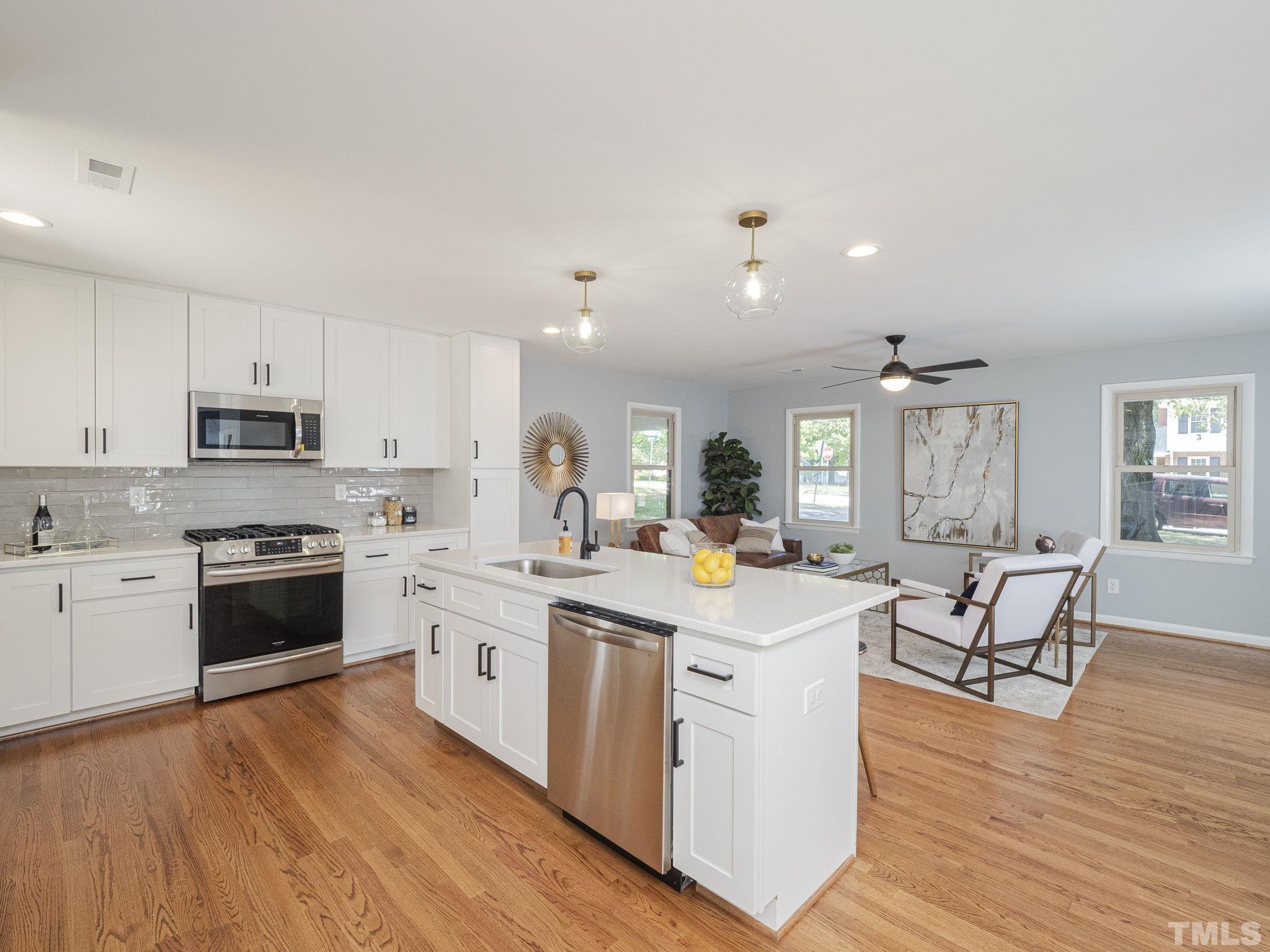 5309 Knollwood Road Raleigh, NC 27609 - Photo 7 of 19 a large white kitchen with stainless steel appliances granite countertop a stove oven a dining table and chairs with wooden floor