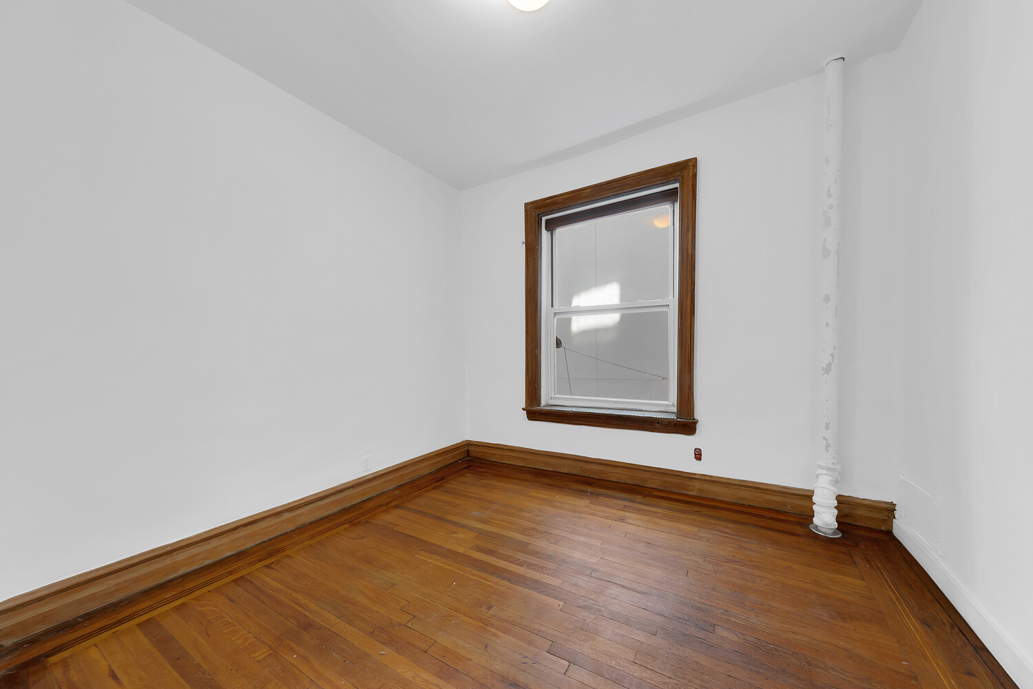 261 West 22nd Street, Unit 11 Manhattan, NY 10011 - Photo 9 of 10 a view of an empty room with wooden floor and a window
