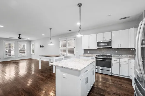 a kitchen with stainless steel appliances granite countertop a sink a stove and a wooden floors