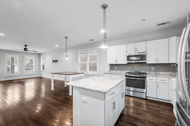 a kitchen with stainless steel appliances granite countertop a sink a stove and a wooden floors