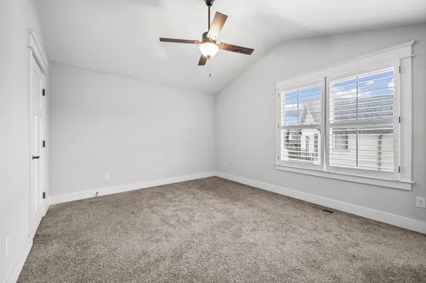 an empty room with windows and fan