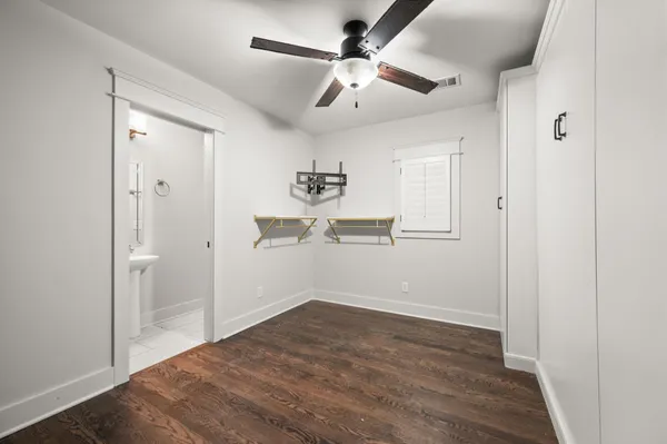 an empty room with wooden floor and ceiling fan