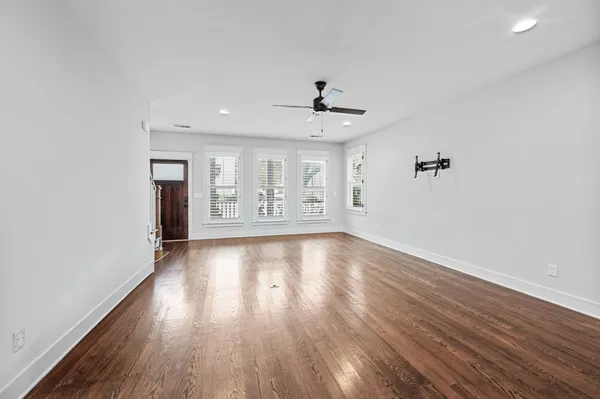 an empty room with wooden floor and windows