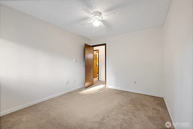 an empty room with a chandelier fan and windows
