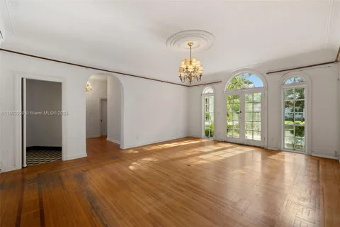 an empty room with wooden floor cabinet and windows