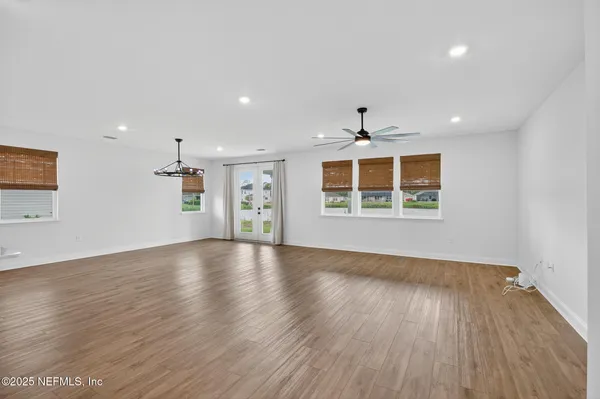 an empty room with wooden floor a ceiling fan and windows