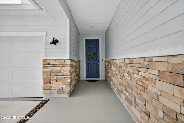 a view of a hallway with a chair and chandelier