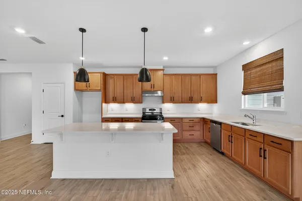 a view of empty room with wooden floor and kitchen