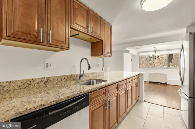 a kitchen with stainless steel appliances granite countertop a sink and dishwasher with wooden cabinets